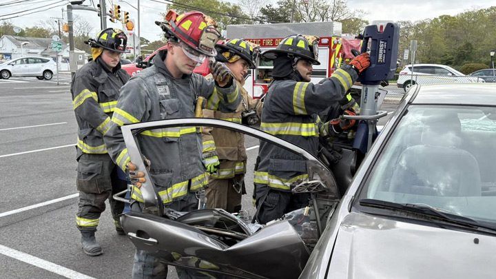 Firefighters using jaws of life on a car door after an accident