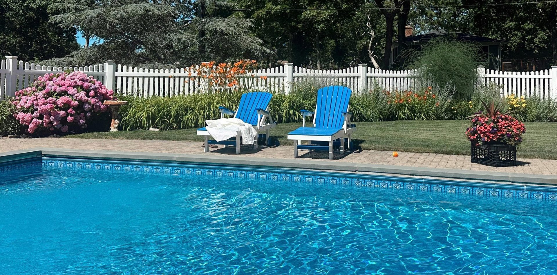 two lounge chairs alongside a backyard pool on a sunny day