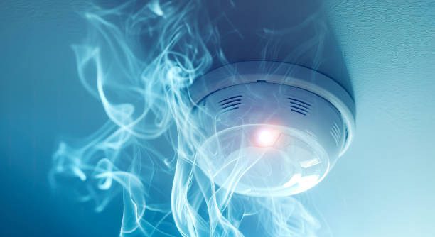 image of a smoke detector mounted to a ceiling with smoke around it